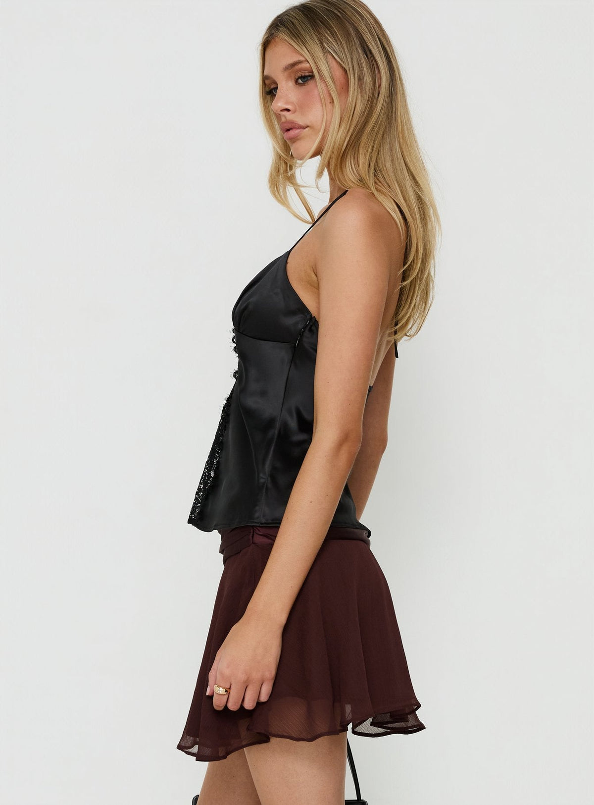 Crafted with asymmetry and flared details, the Emey Asymmetrical Mini Skirt Brown womens-skirts offers a solid maroon design side view of model wearing Princess Polly