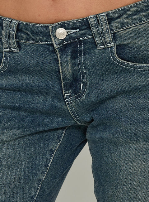 Highlighting the Clynee Ultra Low Rise Bootleg Jeans Dirty Blue in womens-jeans with low-rise waist Princess Polly